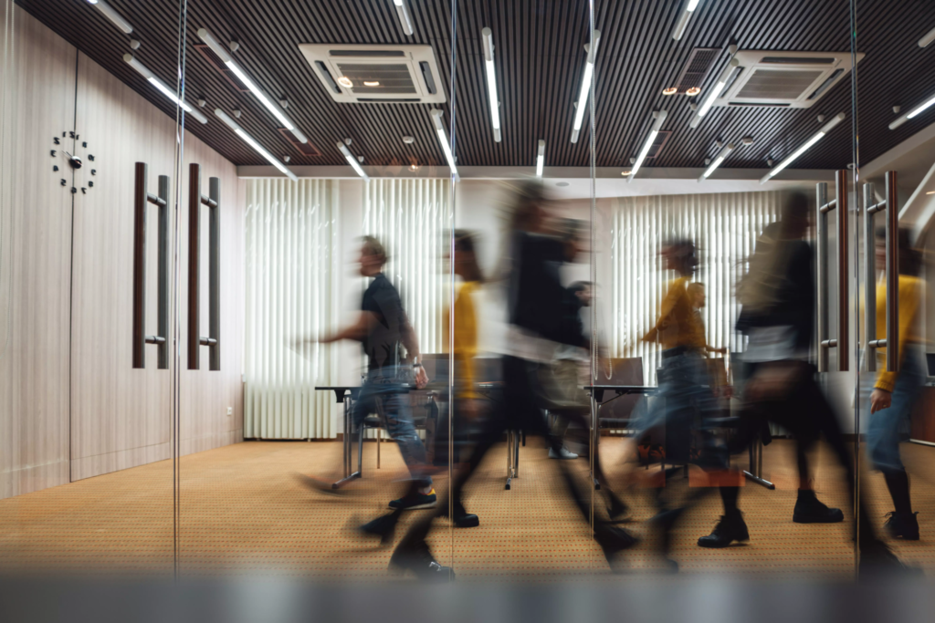 Groupe d'employés de bureau flous et en mouvement marchant dans un couloir de bureau ouvert moderne.