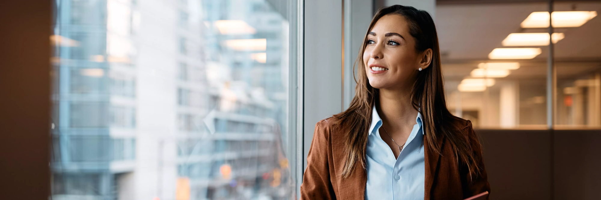 Femme d'affaires regardant par la fenêtre dans un environnement de travail